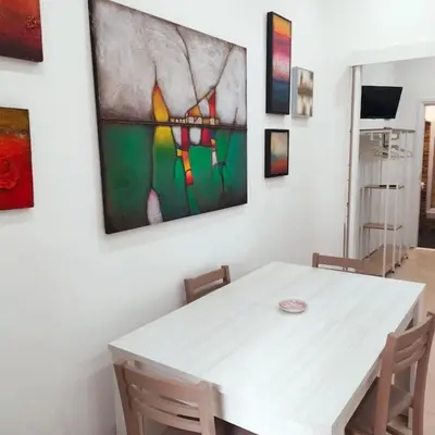 a dining room with a white table and a painting on the wall at La Casetta di Angy in Palermo