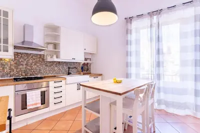 a kitchen with white cabinets and a wooden table at Viola's Luxury House in Palermo