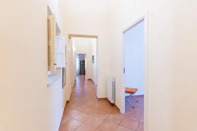 a hallway with white walls and a chair in a room at Viola's Luxury House in Palermo