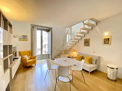 a living room with a table and chairs and a staircase at The Unique Loft Maqueda - in the city centre in Palermo