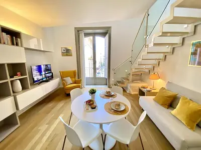 a living room with a white table and chairs and stairs at The Unique Loft Maqueda - in the city centre in Palermo