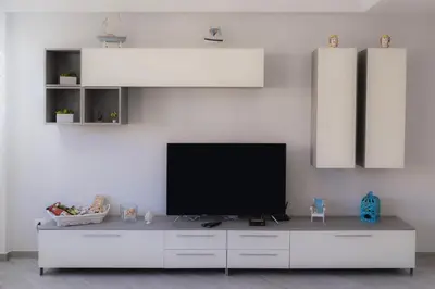 a living room with a television on a white wall at Nelly Casa Vacanze in Porticello