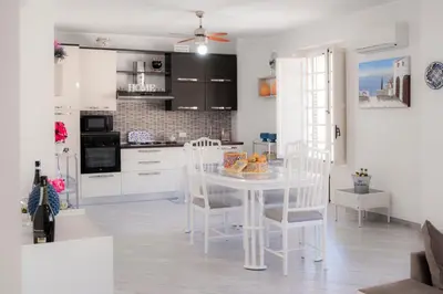 a white kitchen with a white table and chairs at Nelly Casa Vacanze in Porticello