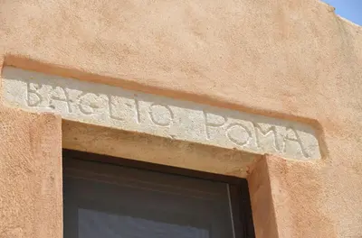 a sign on the side of a building with the name of a pasta farm at Baglio Poma in Castelluzzo