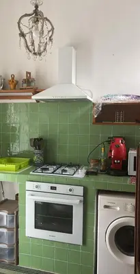 a green kitchen with a stove and a washing machine at Artist penthouse 2 in Palermo