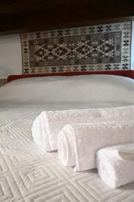 a bed with three rolls of white towels on it at Casamartú Apartment in Palermo
