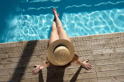 a woman in a hat laying next to a swimming pool at Villa Paradiso in Castelluzzo