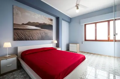 a bedroom with a red bed and a painting on the wall at Sea Sicily View in Bagheria
