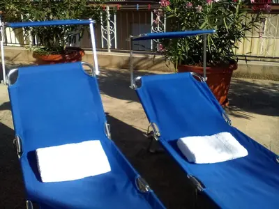 two blue chairs sitting on the street with plants at Il Terrazzo Di Oleandri in Bagheria