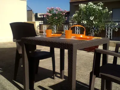 a black table with chairs and orange cups on it at Il Terrazzo Di Oleandri in Bagheria
