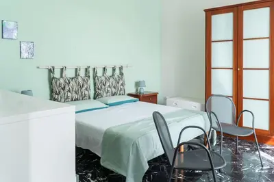 a bedroom with a large bed with two chairs at B&B da Nonna Cicci APT vicino al Teatro Massimo in Palermo