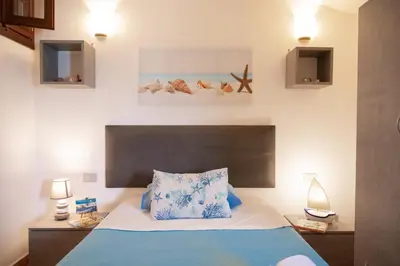 a bedroom with a bed with blue and white pillows at Villa Carilù in Altavilla Milicia