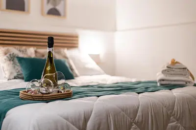 a bottle of champagne and glasses on a bed at Teama House - Appartamento in centro - Politeama in Palermo