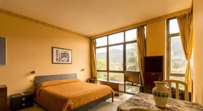 a bedroom with a bed and a table and windows at Cleotto residence case vacanza in Palermo