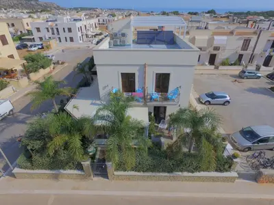 a white house with palm trees in a city at Athena Bed & Breakfast in San Vito lo Capo