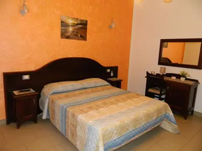 a bedroom with a bed and a desk and a mirror at Baia Santa Margherita B&B in Castelluzzo