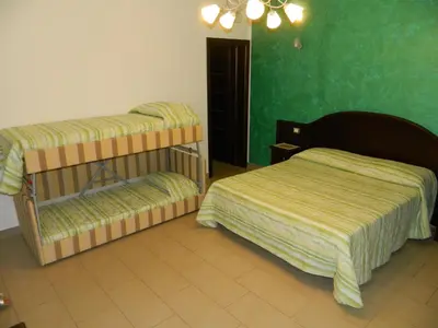a bedroom with two beds and a green wall at Baia Santa Margherita B&B in Castelluzzo
