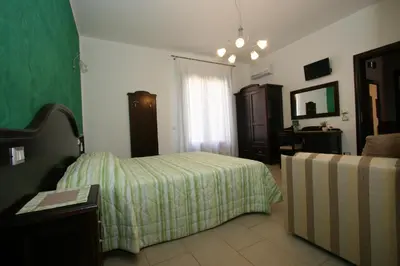 a bedroom with a bed and a table and a couch at Baia Santa Margherita B&B in Castelluzzo