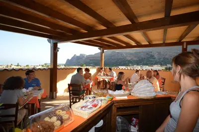 a group of people sitting at tables on the beach at Baia Santa Margherita B&B in Castelluzzo