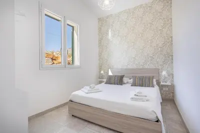 a white bedroom with a bed and a window at Villa Aurora in Balata di Baida