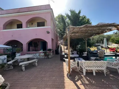 a pink building with a patio and a swimming pool at Villetta dei Tramonti in Trappeto