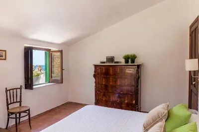a bedroom with a bed and a chair and a window at Villa La Fenice by Wonderful Italy in Castellammare del Golfo