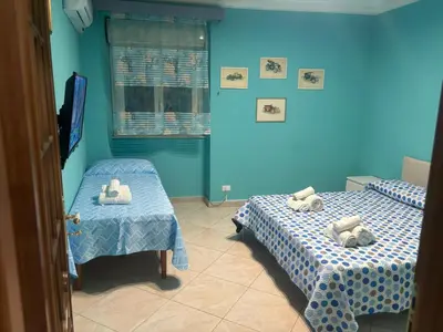 two beds in a room with blue walls at Casa Vacanze Madison Square in Palermo