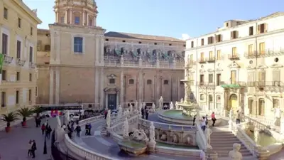 a group of people walking around a building with a fountain at Casa Vacanze Madison Square in Palermo