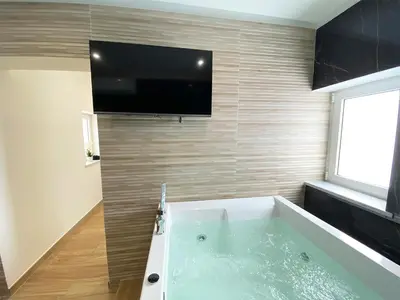 a bathroom with a tub with a tv on the wall at Dimora Sicula Relais - Palermo in Palermo