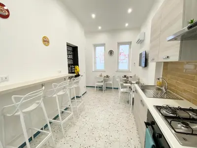 a kitchen with white cabinets and a table and chairs at Dimora Sicula Relais - Palermo in Palermo