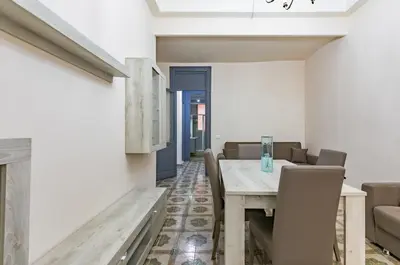 a dining room with a wooden table and chairs at Teatro Massimo Roomy Flat with Covered Terrace in Palermo