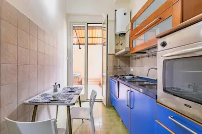 a kitchen with blue cabinets and a table and chairs at Teatro Massimo Roomy Flat with Covered Terrace in Palermo