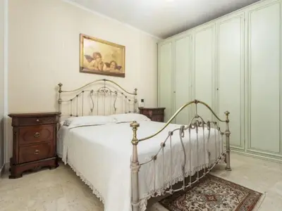 a bedroom with a white bed and a painting on the wall at CASA VACANZE PERLA in Partinico