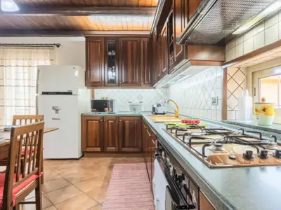 a kitchen with wooden cabinets and a stove top oven at CASA VACANZE PERLA in Partinico