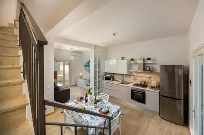 a kitchen with a table and a refrigerator at I Tre Golfi - Villetta Ninfea in San Vito lo Capo