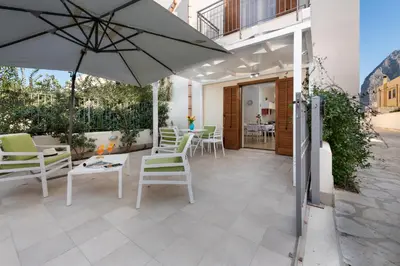a patio with white chairs and an umbrella at I Tre Golfi - Villetta Ninfea in San Vito lo Capo
