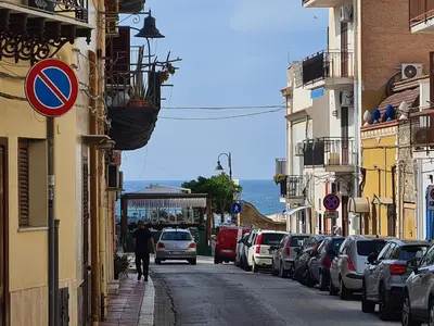 a man walking down a street with cars parked at Holiday House Giorgia in Terrasini