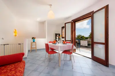 a living room with a white table and red chairs at Paprica&Zenzero in San Vito lo Capo