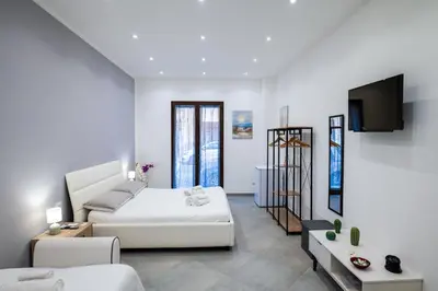 a white room with a bed and a tv at Baron’s Suites in Palermo