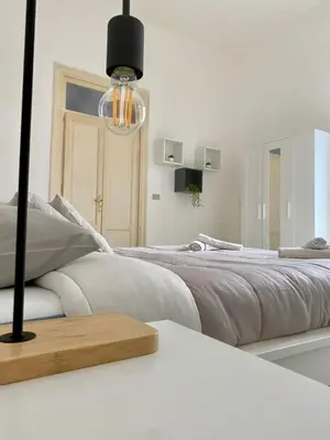 a white bedroom with a large bed and a chandelier at Urban poet retreat - casa di vincenzo e andrea 2 in Palermo