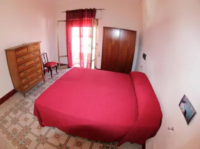 a bedroom with a large red bed and a dresser at La Melagrana in Castellammare del Golfo