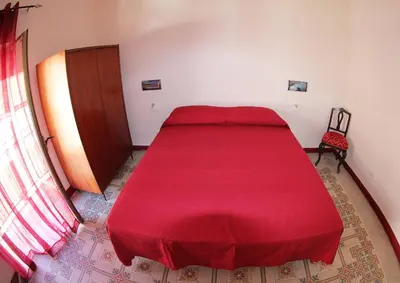 a red bed in a room with a red blanket at La Melagrana in Castellammare del Golfo