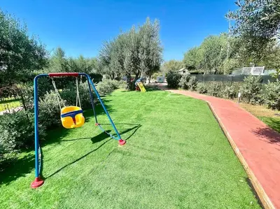 a playground with a swing in the grass at Sicilian Shore Haven, 2 min to SEA in Terrasini