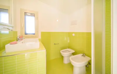 a green and white bathroom with a sink and a toilet at Beautiful Home In Altavilla Milicia in Altavilla Milicia