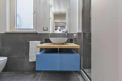 a bathroom with a sink with a bowl on a blue stool at GuestHost - Al Qasr Design and Luxury Flat - Palermo Center in Palermo