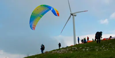a group of people flying a kite on a hill with a wind turbine at Casa Vacanze Karol in Trappeto