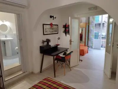 a room with a desk and a hallway with a bedroom at The tailor's house in Palermo