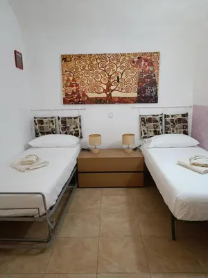 a room with two beds and a painting on the wall at NONNA ADRIANA in Terrasini