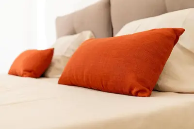 an orange pillow on a bed with white pillows at Casa M al Teatro Massimo in Palermo