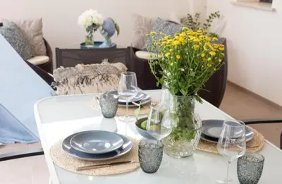 a table with plates and glasses and a vase of flowers at Holiday House Vitruvian in Terrasini